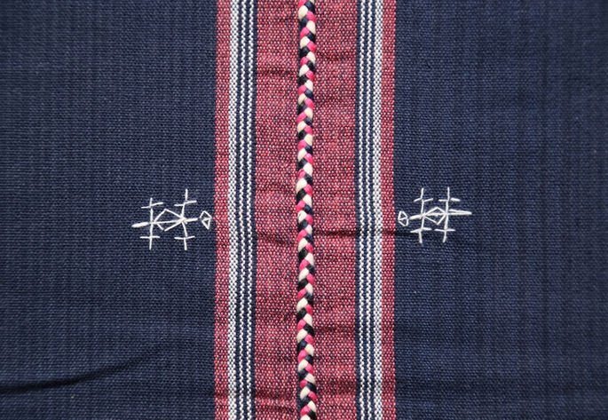 A close-up shot of the white embroideries, showing details on the lizard embroidery and braided threads