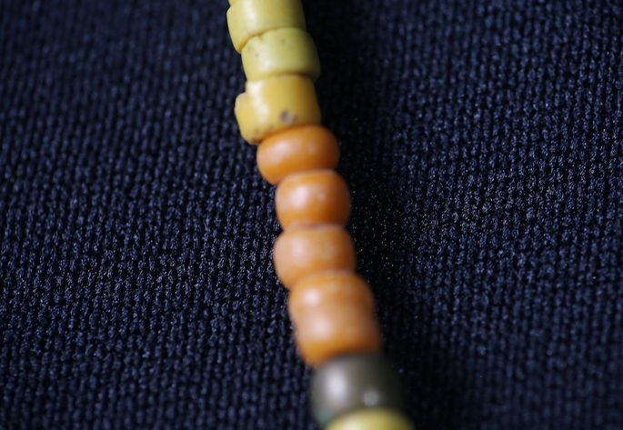 Details of the disk-like yellow beads and the round orange and brown glass beads