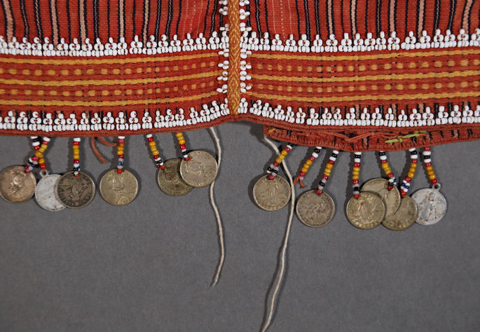 Metal coins are attached to the beaded fringes sewn onto the bottom of the blouse