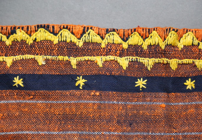 A focused shot on the top edge of the skirt, showing continuous half-diamond embroideries