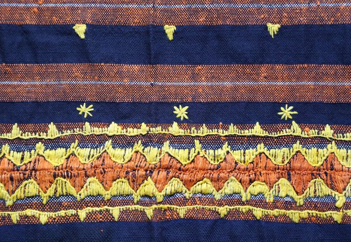 A closer look at one of the panels of the skirt, showing multiple embroideries in yellow and orange