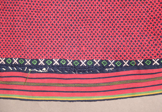 A focus shot on the “X” and diamond motifs found near the loincloth’s striped border edges 