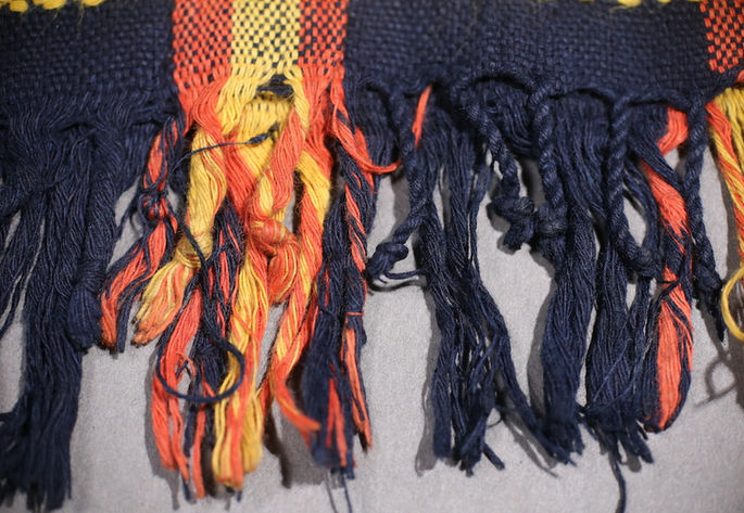 A close-up shot at the loincloth’s fringes: some are knotted; some are braided