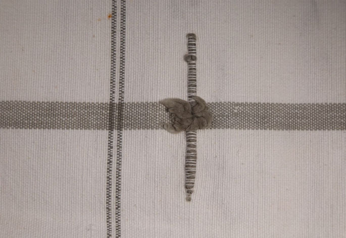 A close-up shot showcasing one of several embossed ornamentations. It includes a pompom-like thread that pops off in the middle of the inserted thread on the textile.