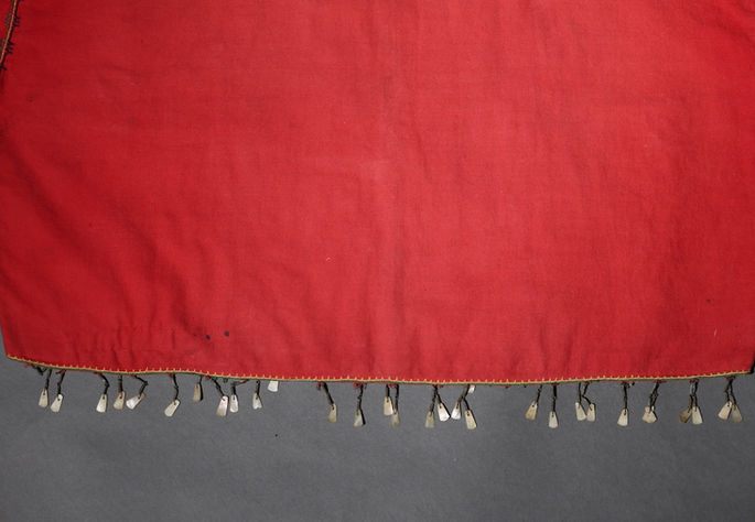 The bottom seam of the blouse is embellished with finely crafted coiled brass wires and shell pendants