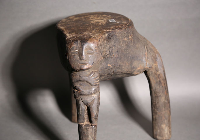 One of the three legs of this wooden stool has an anthropomorphic carving