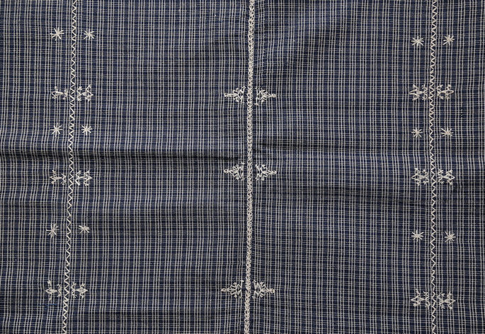 A closer look at the textile’s plaided design and white embroideries