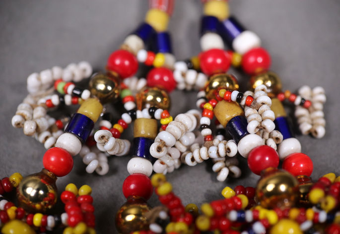 A closer look at the intricate beadwork of the tassel, featuring beads in various sizes, cylindrical and round shapes, and multiple colors including gold