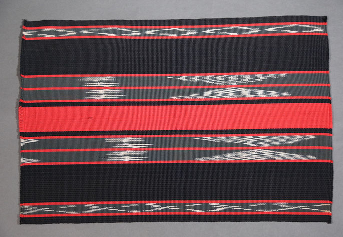 A feature shot of an Ifugao textile design-inspired sample swatch, featuring black, gray, and red stripes, along with traditional motifs created using the Ifugao ikat warp-thread tie-dyeing technique