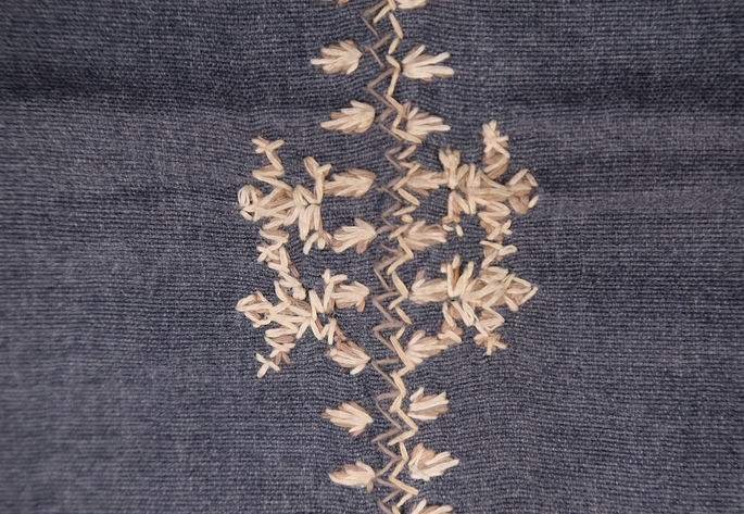 A close-up shot showing the double-outlined embroideries of frog in white and brown threads
