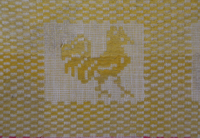 Each of the rooster-like motif appears to be boxed inside the woven grid-like structure on the textile.