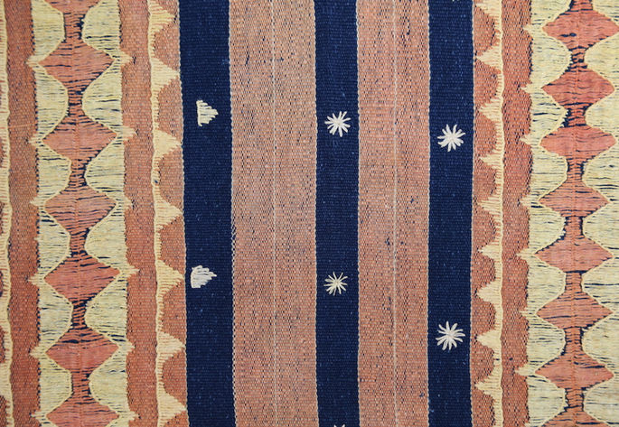 An overview of the designs and embellishments on the cloth, showcasing its stripes and embroidery