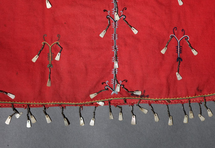 Finely embroidered motifs on the garments are also embellished with coiled brass wires and shell pendants