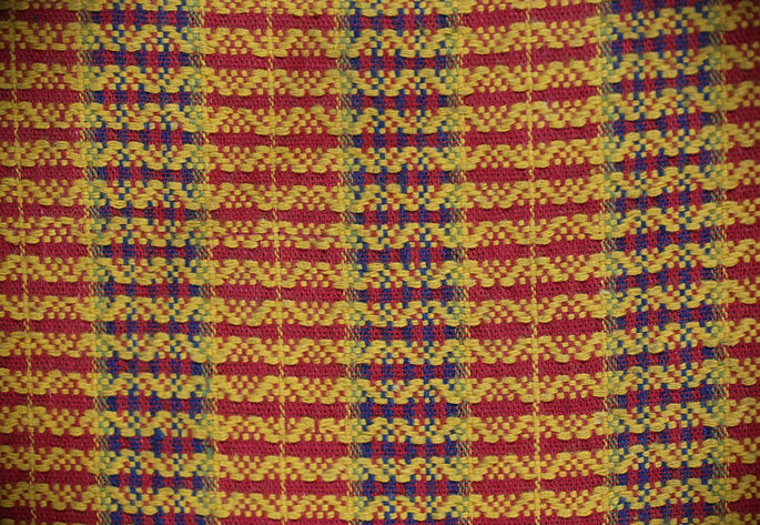 The brocade-woven design on the textile resembles diamonds or zigzags, arranged in stripes with narrow spaces between each one