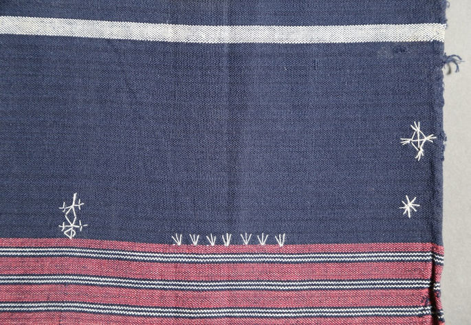 A closer look at one of the outer edges of the skirt, showing various embroideries found near the red, black, and white stripes design at the bottom