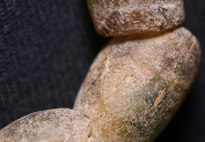A closer look at the necklace beads, highlighting their rough finish and texture