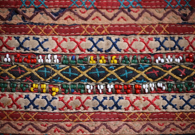A close-up shot highlighting the intricate embroidery and beadwork on one of the appliquéd portions of the trousers