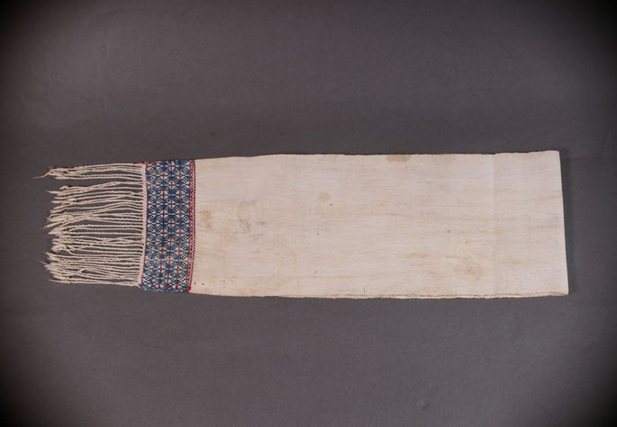 A hero shot featuring a white headcloth with red and yellow-green designs near its two warp ends.