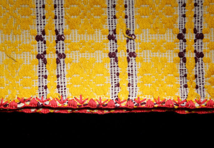 A detailed shot showing one edge of the textile with a red traditional embroidery pattern.