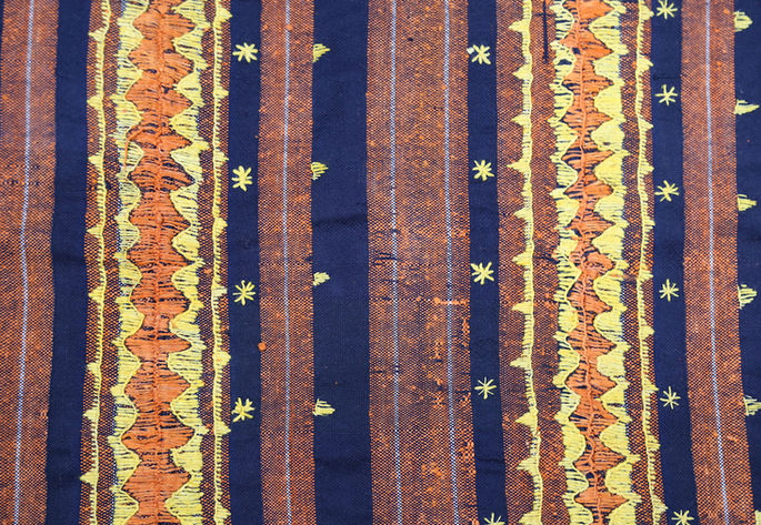 An overview of the designs and embellishments on the cloth, showcasing its stripes and embroidery
