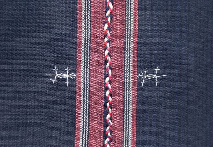 A close-up shot on one of the white embroideries, highlighting the lizard design and braided threads