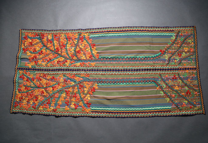 A feature shot of a two-paneled striped skirt, heavily embellished with an embroidery design depicting a tree