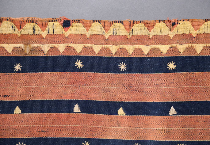 A focused shot on the top edge of the skirt, showing continuous half-diamond embroideries. Asterisk and triangle-like embroidery are also shown in detail