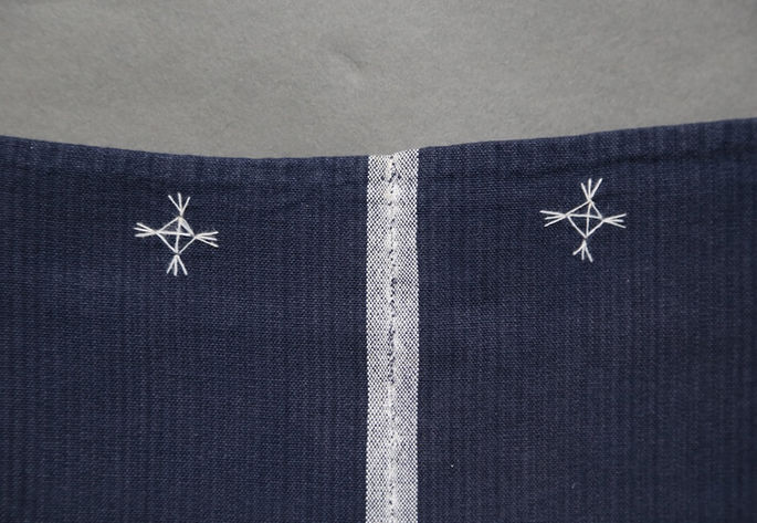 Details of a diamond-shaped white embroidery at the side edges