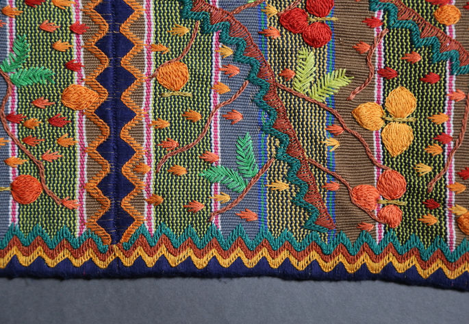 The four sides of the skirt are embroidered with a sequence of blue-green, brown, orange, and indigo zigzag patterns