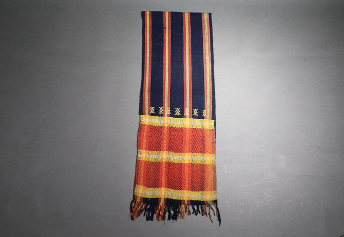A hero shot of an indigo-colored loincloth with orange and yellow striped bands and braided knotted fringes