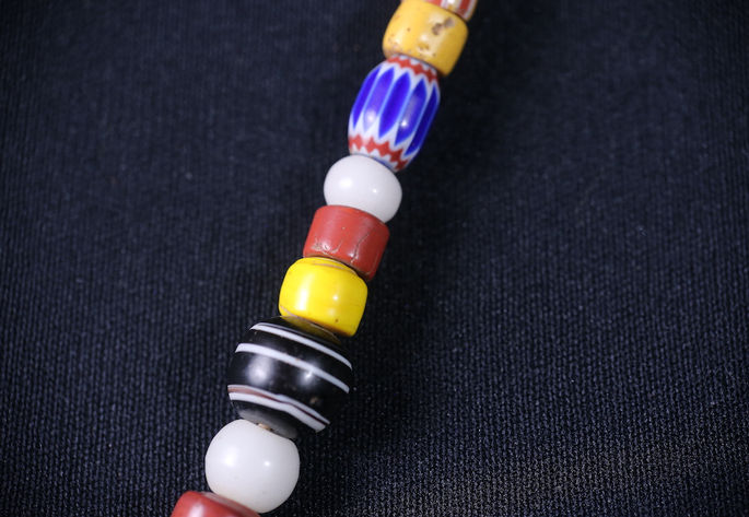 A chevron or paraggi followed by white, red, yellow opaque beads, and a round, banded agate bead