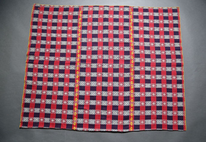 A hero shot featuring a three-paneled textile in red,blue, and white, adorned with small diamond motifs and fine embroidered joinery.