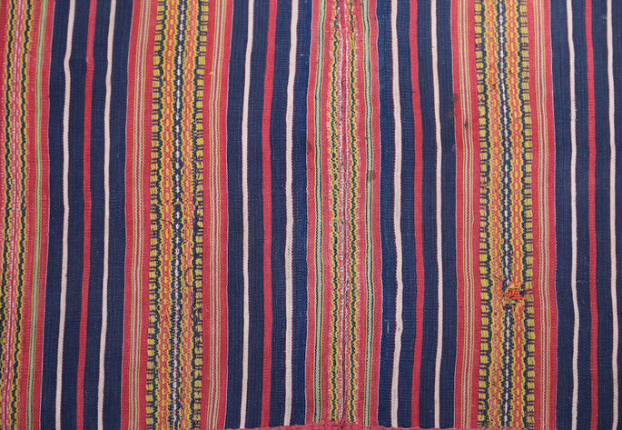 Thick and narrow stripes are woven into the skirt, with the thicker stripes featuring geometric and linear designs in blue, yellow, and red