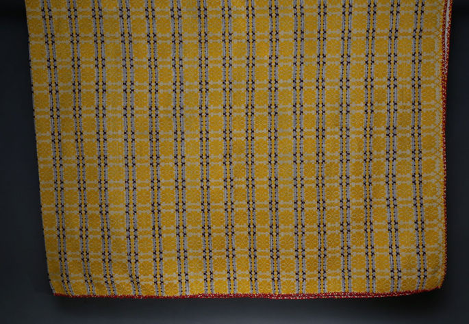 A hero shot of a yellow brocade-woven blanket with tiny flower motifs.