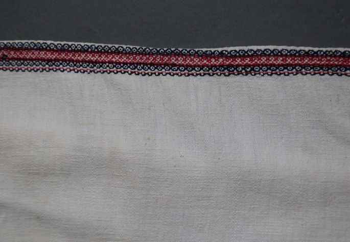 The warp ends feature diamond-like and circular patterns created with black/indigo and red woven threads