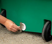A hand opening the drain plug on a green wheeled cooler.