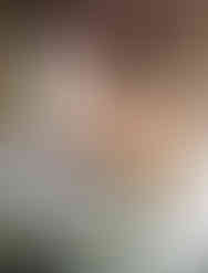 Lighty, airy bedroom, yellow accent pillows, white bedding. Ball of green velvet yarn and a handmade velvet scarf are on the bed. A wood yarn holder shaped like a cauldron is there.