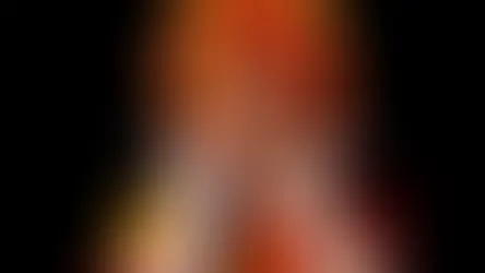 Isabelle Drummond caracterizada como Emília, com peruca laranja e amarela, figurino vermelho e amarelo e luvas brancas.