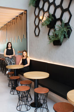Duas mulheres sentadas em um café com decoração moderna.
