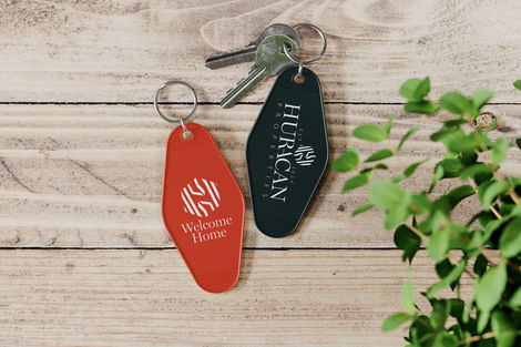 a hurricane properties keychain sits next to a welcome home keychain