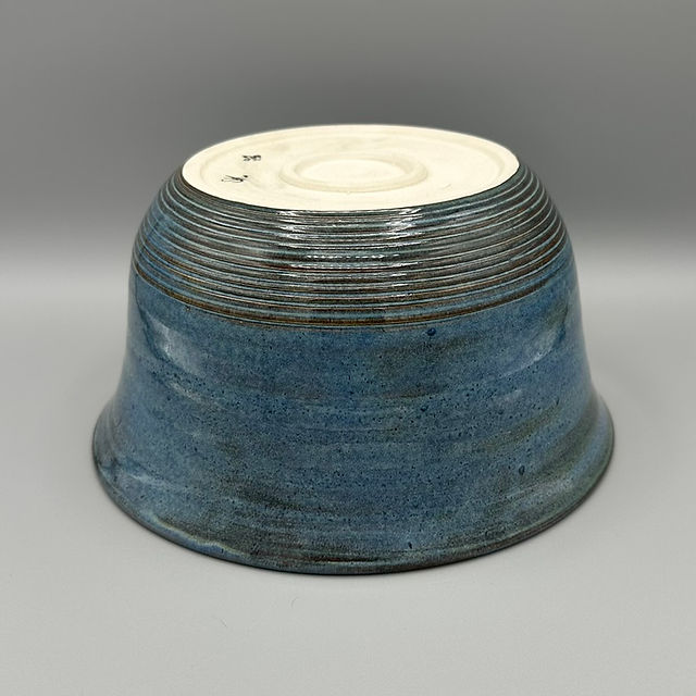 A ceramic bowl with a textured, ridged base and a blue glaze, displayed upside down.