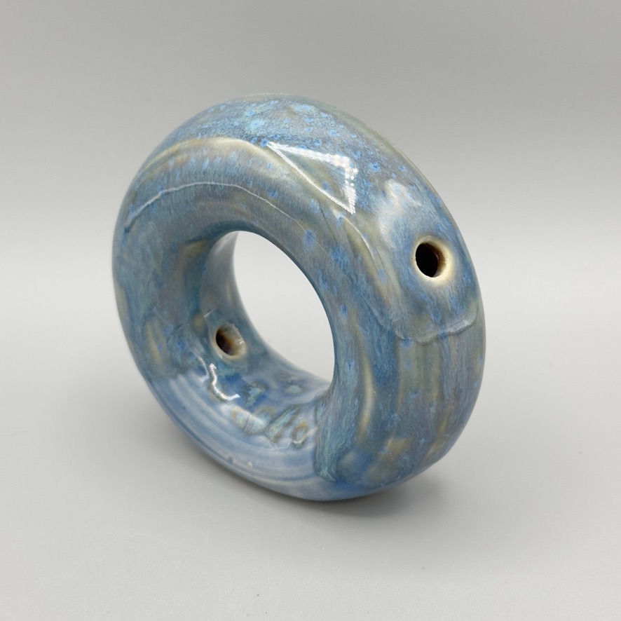 Handcrafted circular donut vase in blue opal glaze with oyster tones, modern ceramic decor piece.