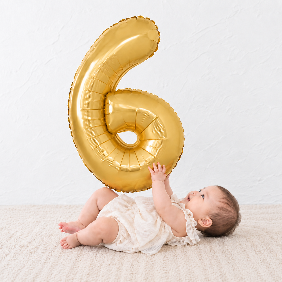 ゴールドの大きな数字「6」のナンバーバルーン(数字風船)を両手で抱えて寝転ぶ赤ちゃん。ハーフバースデー(生後6ヶ月)や6歳の誕生日飾り付け、記念撮影プロップスに最適なアルミバルーン。