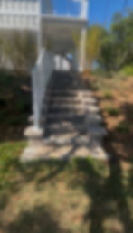 Outdoor stone staircase with white railing leading to house