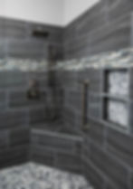 Modern walk-in shower with dark tiles and built-in bench