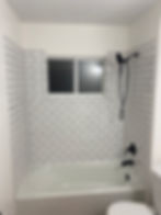 Modern bathtub with white subway tile and black fixtures.