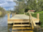 Wooden dock with stairs leading into calm water.