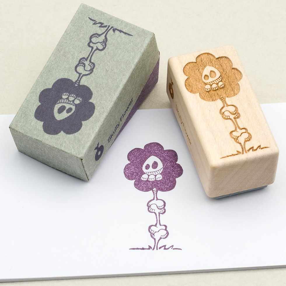 Holzstempel mit Totenkopf-Blume: links graue Schachtel, rechts Holzstempel, darunter lila Abdruck auf weißem Papier.