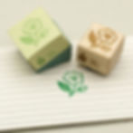 Motivstempel aus Holz, der eine Teeblüte zeigt. Dazu die Schachtel und die Stempelung in saftgrün auf Papier.