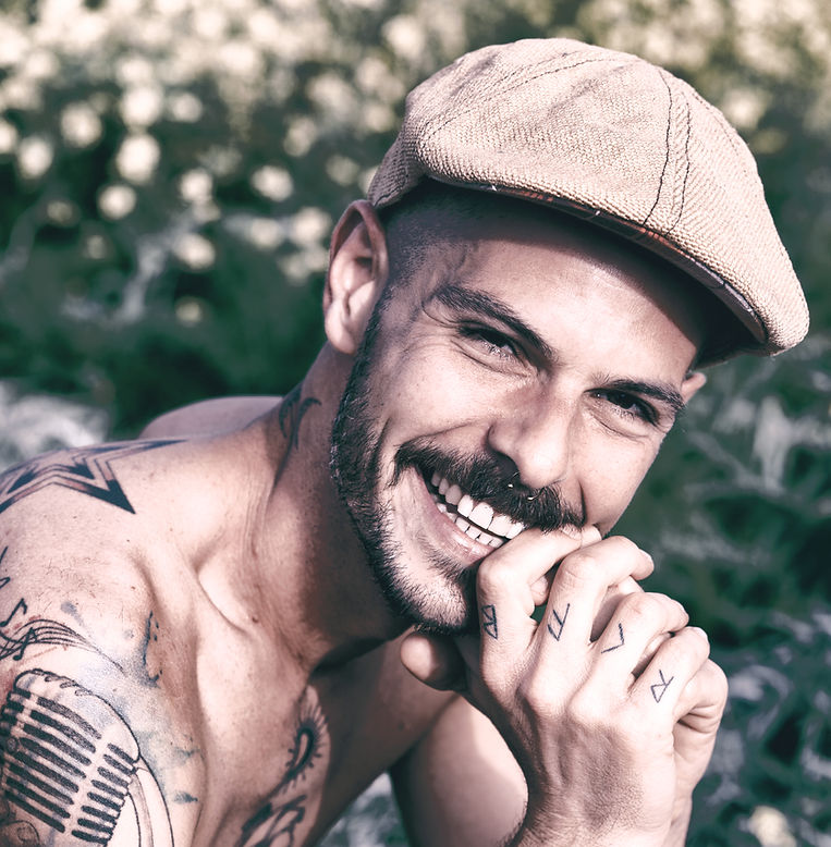 Smiling man with tattoos and newsboy cap